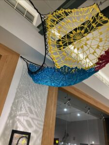 multi-colored crochet hammock hanging on gallery