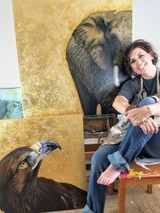 painter next to her wild animal canvas paintings